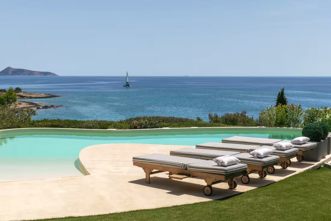 Poolside sunbeds overlooking the Aegean